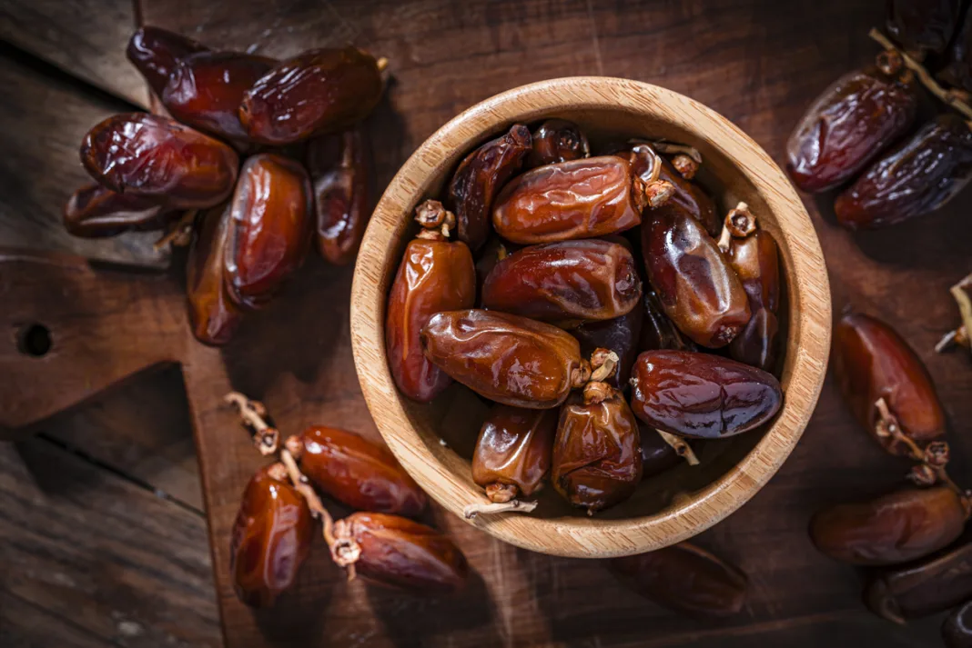 Overhead view of organic dried dates in a wooden bowl